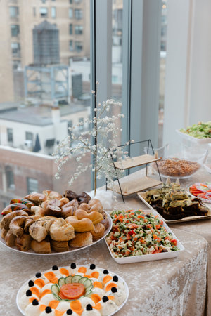 A colorful assortment of dishes on a table showcases various foods with a view of the city skyline...