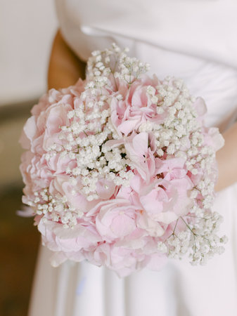 A bride holds a stunning pink and white bouquet filled with delicate flowers, adding charm to her...