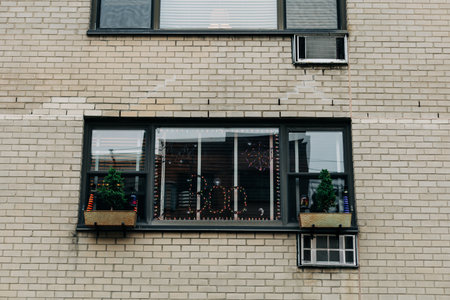Brightly decorated apartment window showcasing festive lights and plants during the evening in a...