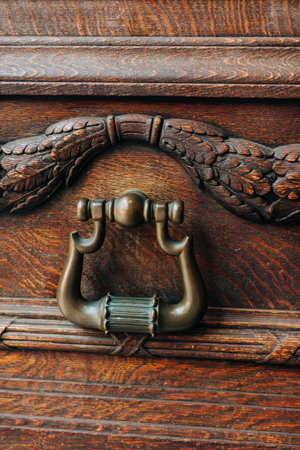 Ornate wooden chest with detailed carvings and antique metal handle in warm lighting
