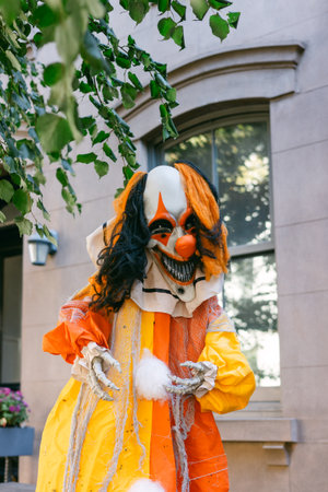 A clown with an unsettling smile stands outside a building, bringing a vivid, playful, yet eerie vibe.の写真素材