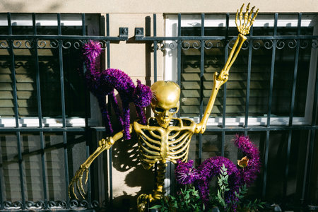 A golden skeleton waves in excitement next to a purple cat, adding a festive touch to a Halloween display outdoors.の写真素材