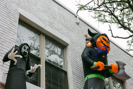Halloween decorations featuring inflatable characters on a building in a festive neighborhood during...