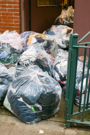Bags of donated clothes piled near entrance of a building on a busy city street in autumn