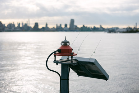 A solar sensor on a dock, city skyline and water in the background, under cloudy skies.の写真素材
