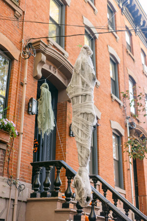 Spooky figures hang from a brownstone in a vibrant neighborhood, celebrating Halloween during the fall season.の写真素材