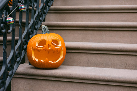 A carved pumpkin with a spooky face sits on the porch steps, adding festive charm to the home during Halloween season.の写真素材