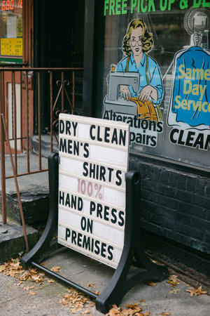 Sign outside a dry cleaning shop shows available services for men's shirts during a calm fall day.の写真素材