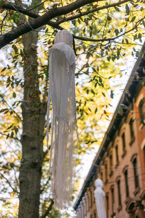 White fabric hangs from a tree branch among yellow leaves in a city setting, evoking a serene autumn atmosphere.の写真素材