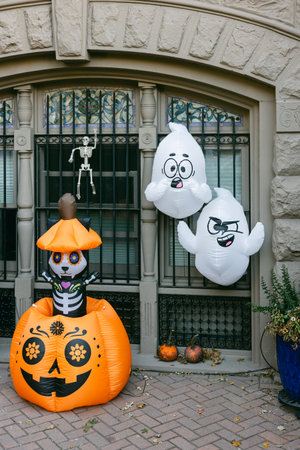 A festive scene has an inflatable skeleton in a pumpkin, with floating ghosts in a city backdrop.の写真素材