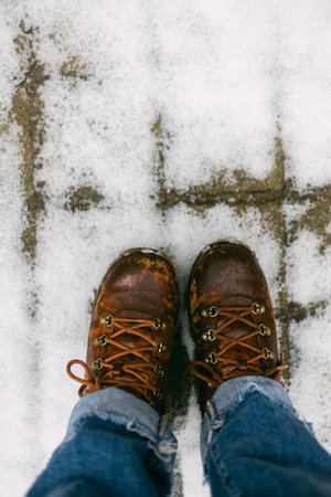 Boots stand on a snow-covered path, showing signs of adventure and the chill of winter.