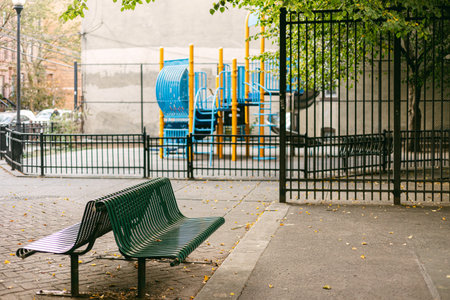 Colorful playground equipment sits unused while empty benches wait for visitors in a peaceful urban park.の写真素材