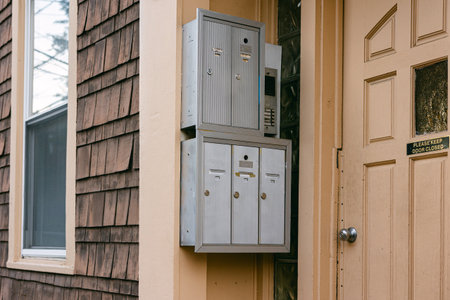 Five mailboxes are mounted by a door, showcasing a modern design and a doorbell panel for visitors.