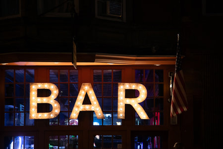 A large, illuminated bar sign stands out against the night sky, inviting guests into the lively establishment.の写真素材