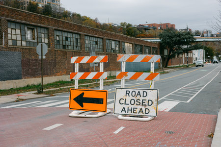 Road closure signs block the path in a city setting, indicating a construction or repair project ahead.の写真素材