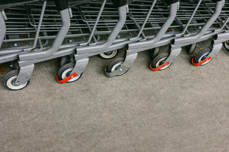 Several shopping carts are neatly lined up, resting on a gray concrete surface in a retail environment.の写真素材