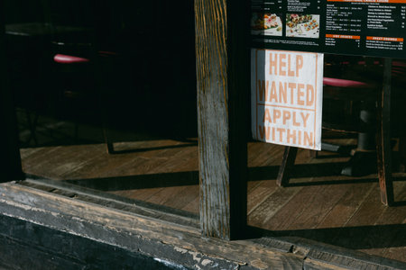 A help wanted sign hangs prominently in a restaurant window, inviting job applicants to apply for open positions.の写真素材