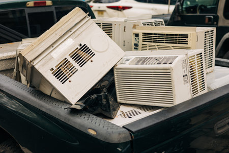 Multiple discarded air conditioning units are stacked in a truck bed, ready for recycling on a clear day.の写真素材
