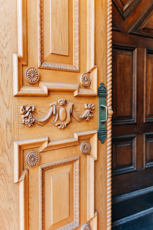Beautifully crafted wooden door features detailed carvings and a shining brass handle, welcoming...