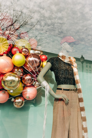 A stylish mannequin dressed in a black top and wide pants stands next to bright holiday decorations in a boutique.の写真素材