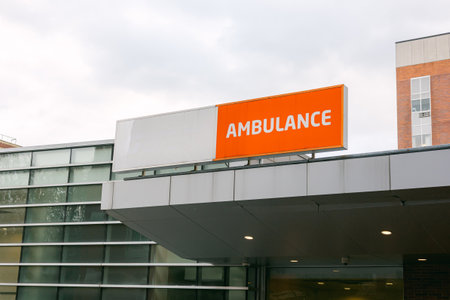 An ambulance sign stands out against a modern building in an urban area on an overcast day.の写真素材