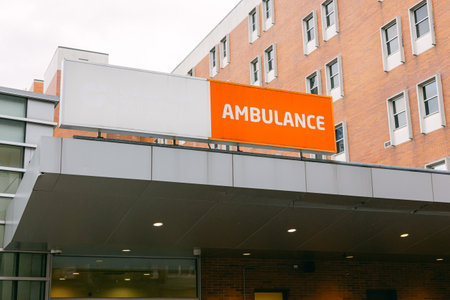 Orange ambulance sign outside a hospital building during cloudy weatherの写真素材