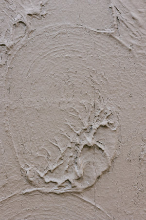 Textured wall with circular patterns and smooth finish in neutral tones during daylightの写真素材