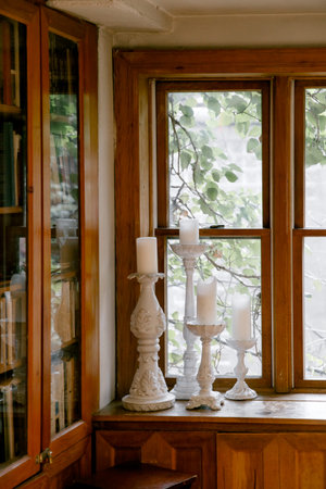 A sunny library corner features decorative candles on tall holders and a view of leaves through the...