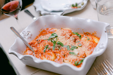 Freshly prepared ravioli topped with vibrant tomato sauce and herbs is a perfect choice for a dinner gathering.の写真素材