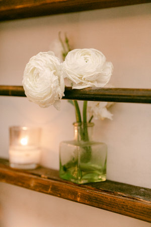 White flowers sit in a green glass vase next to candles, enhancing the warm ambiance of the room.
