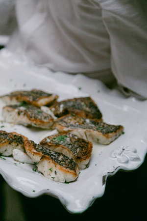 Deliciously grilled fish garnished with herbs served on a stylish platter during a casual outdoor...