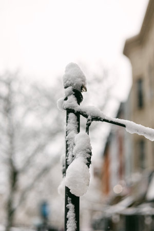 Snow sits on a sign and street as winter weather covers the town and buildings nearby.の写真素材