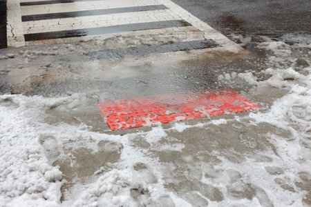 Snow and water mix at a street crossing with a clear bright marker on the pavement in a winter city settingの写真素材
