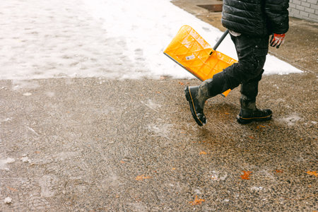 Person walks with yellow sled on snow-covered ground during winter season in urban areaの写真素材