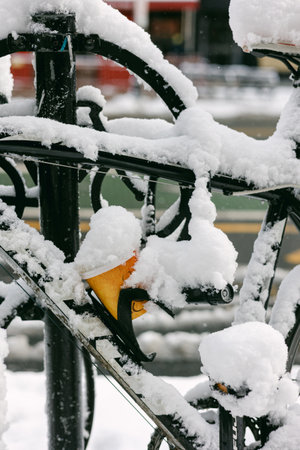 Bicycle stationary at a bike rack with snow covering parts of the bike on a winter day in the city.の写真素材
