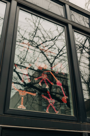 Colorful stick figures in a window show various poses and movements with trees visible outside in daytime.の写真素材