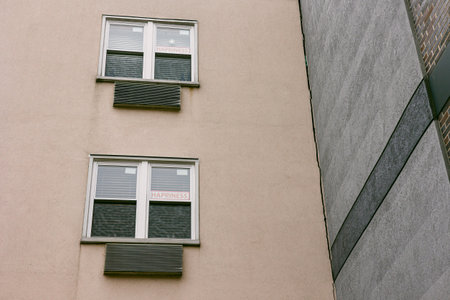 Two windows on a building show signs with the word happiness during daylight hours in an urban area.