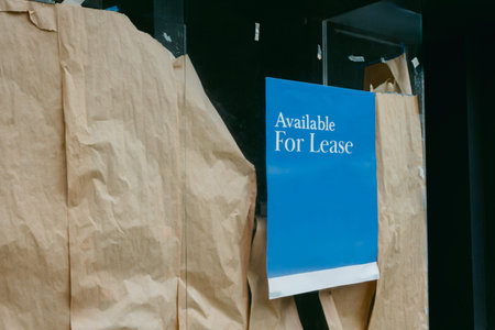 Business storefront shows a lease sign along with brown paper covering the windows. This space is currently available.の写真素材