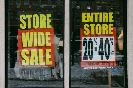 Store front displays sale signs for entire inventory with discounts clearly marked in a bustling shopping location.の写真素材