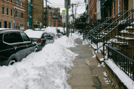 Snow piles along a sidewalk with parked cars on a cold winter day in a city neighborhood.の写真素材
