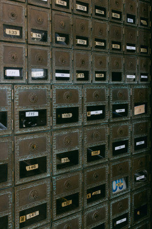 Many mailboxes are lined up on a wall in a city building showing numbers and labels.の写真素材