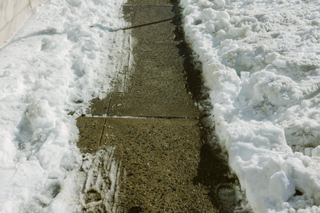 Snow is pushed aside to create a clear walking path on the sidewalk during winter weather.の写真素材
