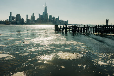 City skyline stands tall above water with ice floating and a clear sky during daytime hours.の写真素材