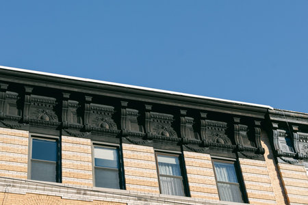 A view of a building's upper section showing detailed design along the cornice while the sun shines in the sky.の写真素材