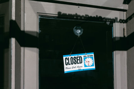 A sign hangs on the door stating the store is closed and asks people to call again later.