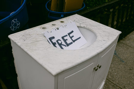 A sink sits on the pavement beside a recycling bin, marked with a sign that says free.の写真素材