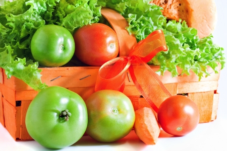 Orange basket lie on the table full of ingredients for the salad   green and red tomatoes, fresh salad, orange carrot and pumpkin  Isolated objects on white background の写真素材