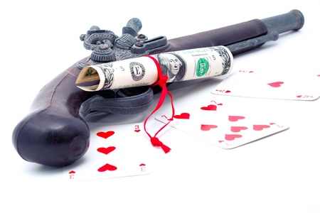 Money revolver and three cards  three, seven and ace lie on the table  Playing cards suit is hearts  One dollar USA note is twisted up in a tube and bandaged with red ribbon の写真素材