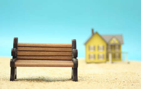 Park Bench on Sand With House in Background, Shallow DOFの写真素材