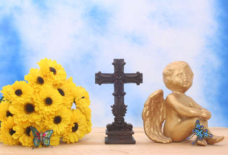 Flowers and Angel with Cross and Butterflies on Blue Sky Backgroundの写真素材